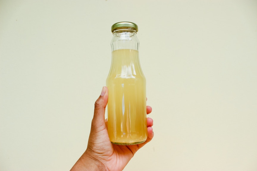 A hand holds a bottle of apple cider vinegar with a gold top